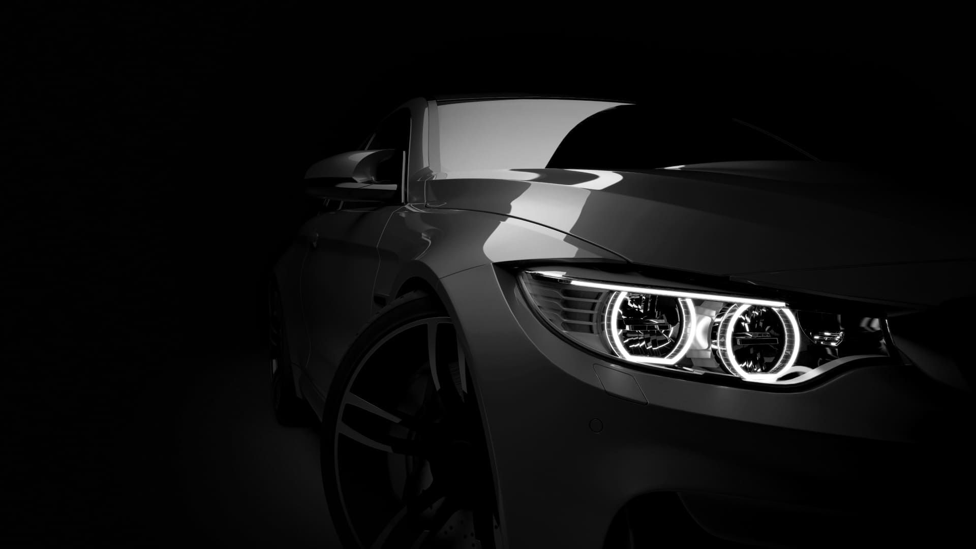 Dramatisch inszeniertes Sport-Coupé in Grau-Metallic vor dunklem Hintergrund.